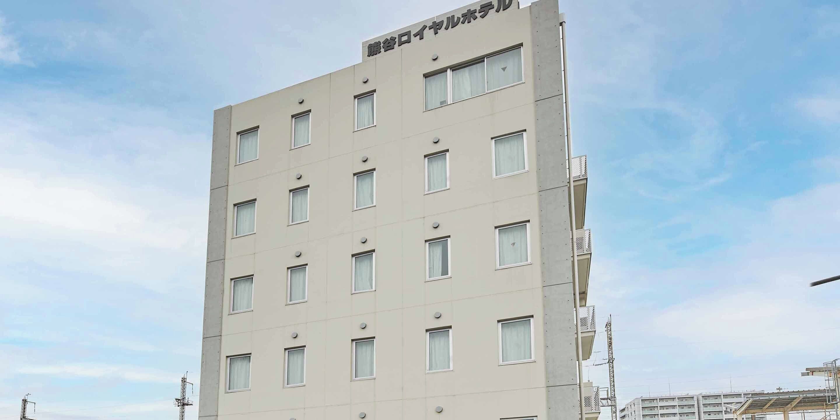 A multi-story building with a flat facade, numerous windows, and a sign at the top.