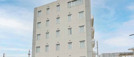 A multi-story building with a flat facade, numerous windows, and a sign at the top.