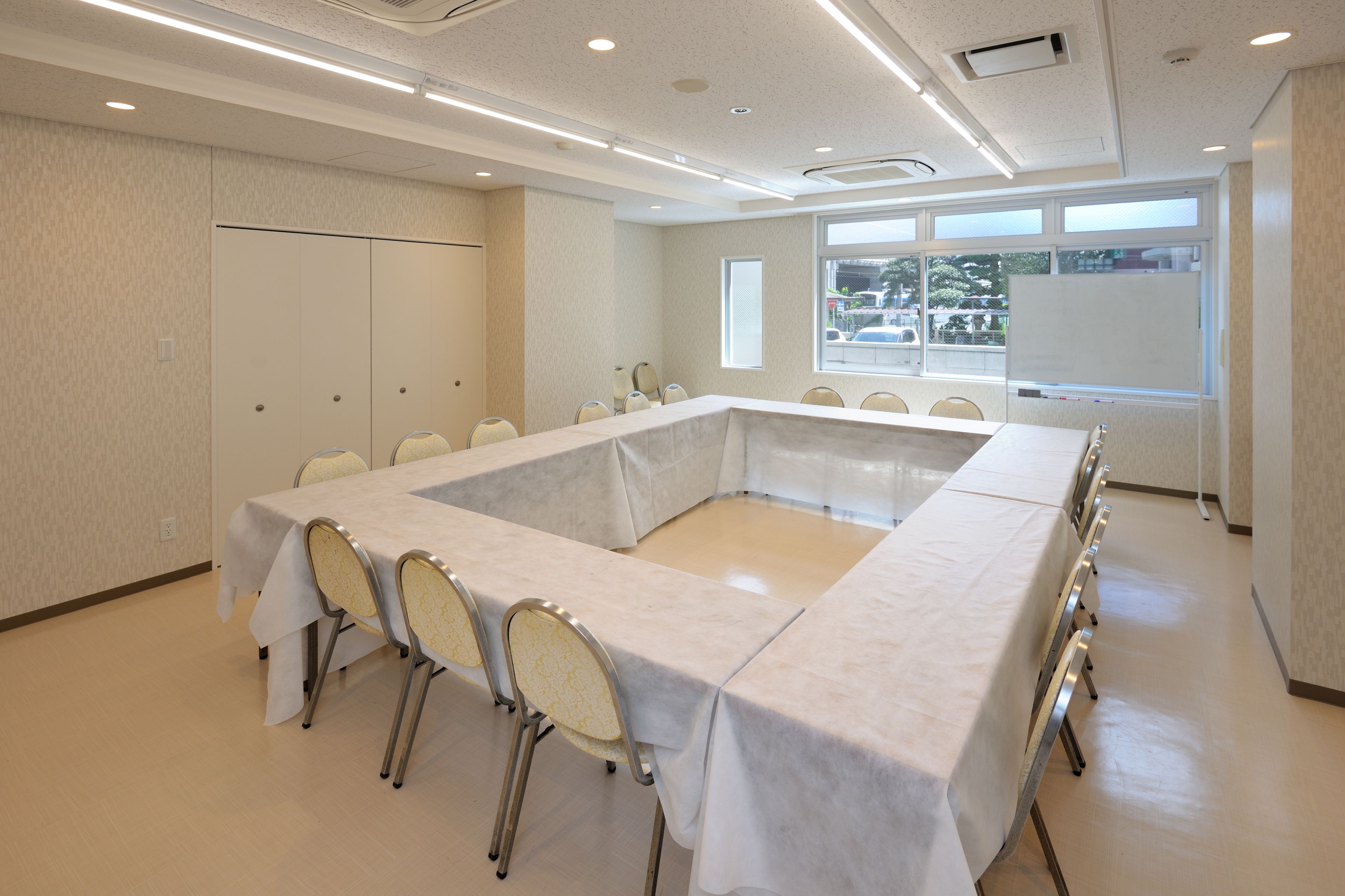 A conference room with a long table, chairs, and a whiteboard.