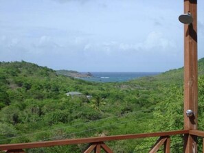 A wooden structure with a metal railing, overlooking a coastal landscape with greenery and a view of the sea. - Sea view apartment with Quietness and relaxation. (Gros Islet)