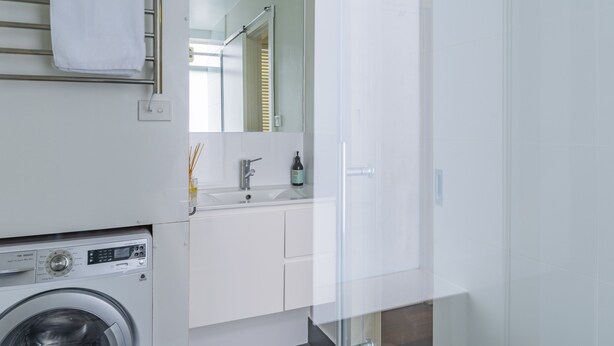 Un baño moderno con lavadora, un lavamanos con espejo y un perchero para toallas.
