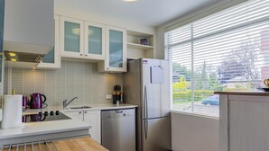 Una cocina moderna con armarios blancos, un refrigerador de acero inoxidable y una ventana con persianas.