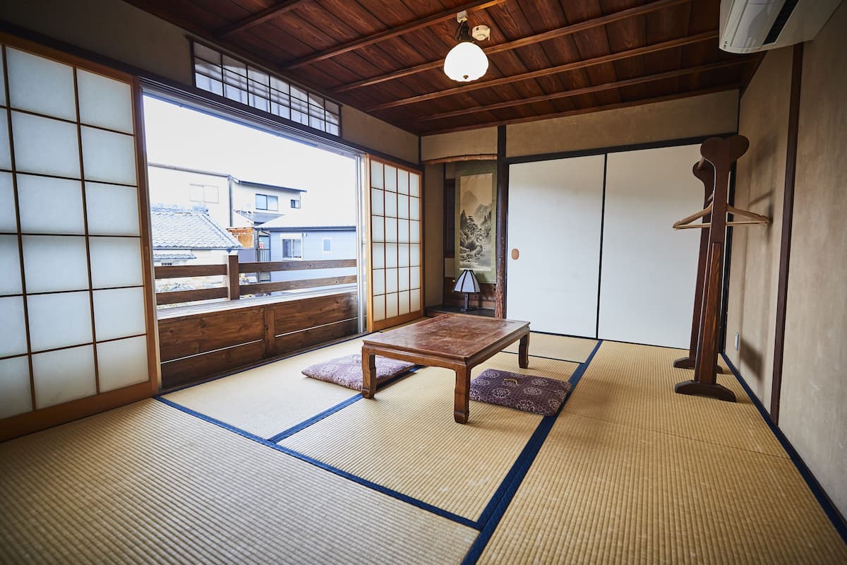 Um quarto japonês tradicional com tatames, uma mesa de madeira e biombos shoji.