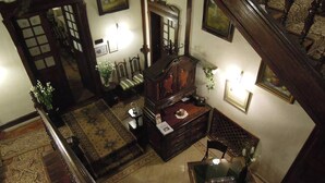 Amplia sala de estar con una escalera de madera grande, un tapete estampado, un mueble de madera y una mesa de centro de vidrio.