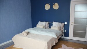 A bedroom with a bed, a door, and a blue wall.