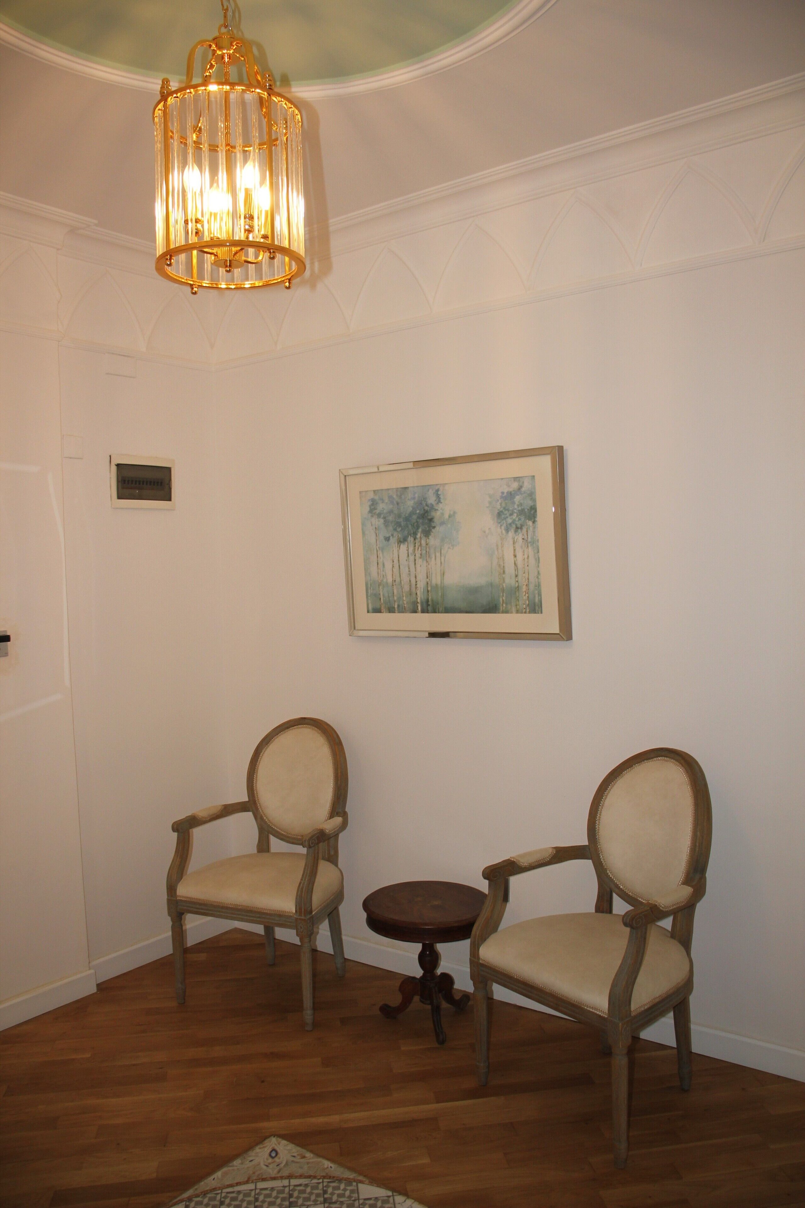 Quarto com duas cadeiras, uma mesa pequena e um candelabro.