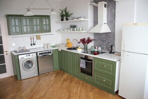 A kitchen with green cabinets, a washing machine, a sink, and a refrigerator.