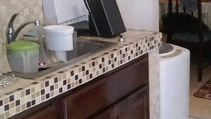 Cozinha com armários de madeira, painel de azulejos atrás da bancada, pia e bancada com porta-facas.