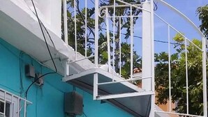 Um edifício azul-turquesa com uma escadaria espiral branca que leva a uma varanda.