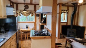 Una cocina acogedora con vigas de madera, estufa, microondas y cafetera.