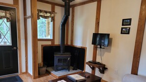 Una sala de estar acogedora con una chimenea de leña, un televisor en la pared y un sofá cómodo.