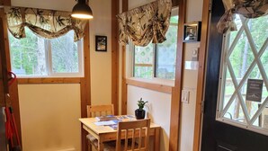 Una habitación acogedora con una mesa de madera, sillas, un reloj y una puerta con ventanal.