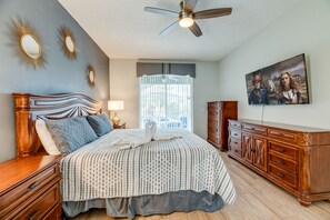 A bedroom with a bed, dresser, vanity, and a ceiling fan.