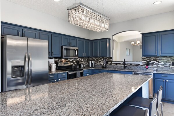A modern kitchen with granite countertops, stainless steel appliances, and blue cabinetry.