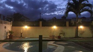 Une piscine à bord incurvé, entourée d’un petit muret et agrémentée de plantes en pot.