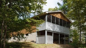 Ein modernes, zweistöckiges Haus mit einer Holzterrasse und einer überdachten Veranda.