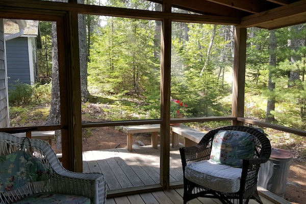 Screened porch looking out to deck and back of boathouse