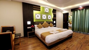 A hotel room with a large bed, wooden flooring, a green curtain, and a modern wall design. - Hotel Nalanda Ladakh (Leh)