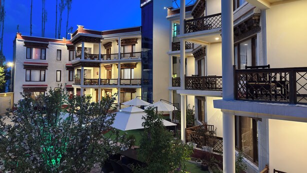 A multi-story hotel with balconies, outdoor seating, and a garden area. - Hotel Nalanda Ladakh (Leh)