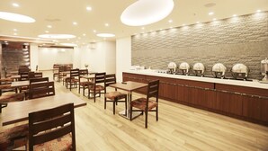 A restaurant with wooden tables and chairs, a brick wall, and a long counter with decorative lamps. - Pals Inn (New Delhi)