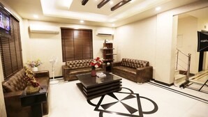 A modern living room with two brown leather sofas, a glass coffee table, and a decorative vase. - Pals Inn (New Delhi)