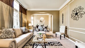 Ein Wohnzimmer mit einer Couch, Sesseln, einem Couchtisch und einer Chandelüster.