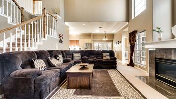 Relax in this inviting living room with a grand staircase, fireplace, and large window.
