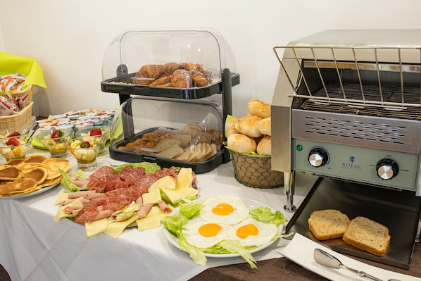 A buffet with various food items including bread, eggs, meats, and salads.