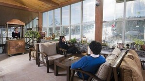 A spacious lobby with large windows, a reception desk, and comfortable seating areas. - Hotel Camkar (Sarikamis)