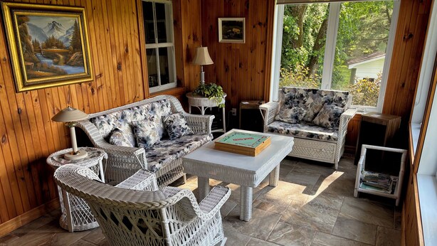 Une pièce chaleureuse avec des murs en bois, un canapé, deux fauteuils, une table basse et une petite table avec une lampe.