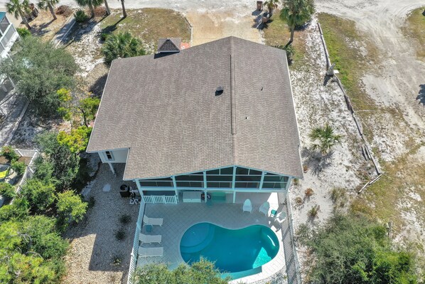 A large house with a swimming pool, a covered patio, and a fenced yard.