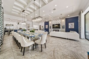 A spacious living area with a dining table, white sofas, and a large TV. - The Portal at Reunion | 9 Bed 10.5 Bath, Southwest Facing Pool Villa with Theater Room (Four Corners)