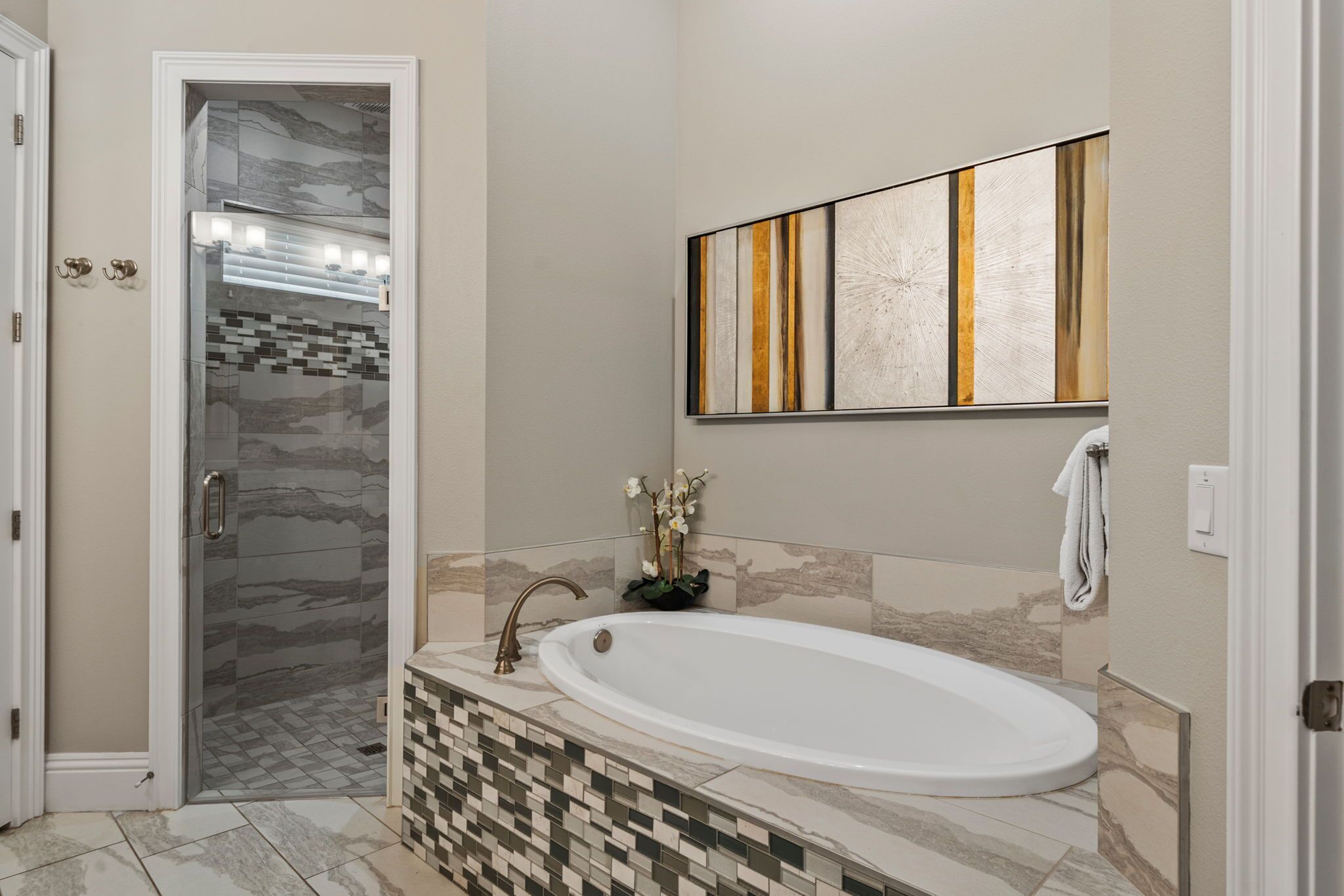 Une salle de bain dotée d’une douche à parois de verre, d’une baignoire sur pieds et d’un meuble-lavabo fixé au mur.