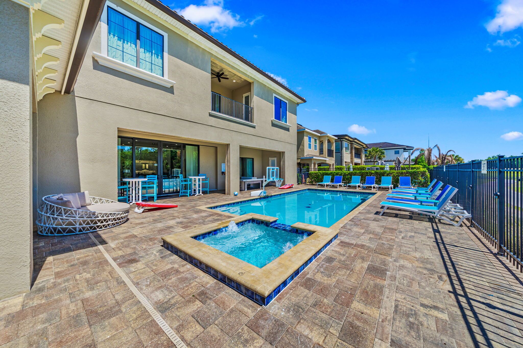 A swimming pool with lounge chairs, a hot tub, and a covered seating area.