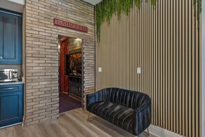 Un intérieur moderne avec un mur en briques, un canapé noir et un panneau indiquant « PLATEFORME 9 ».