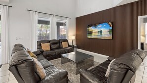 A modern living room with leather sofas, a glass coffee table, and a large painting on the wall. - ✦ 5min to Disney ✦ 6BR/5.5BA ✦ Private South Pool ✦ A/C Game Room ✦ Sleeps 14 (Kissimmee)