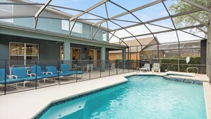 An indoor swimming pool with blue-tiled edges, surrounded by lounge chairs and a covered seating area. - ✦ 5min to Disney ✦ 6BR/5.5BA ✦ Private South Pool ✦ A/C Game Room ✦ Sleeps 14 (Kissimmee)