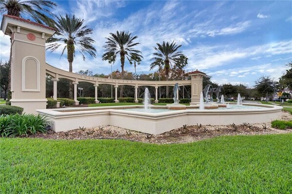 A landscaped area with a fountain, palm trees, and a building with a sign reading "Emerald Island".