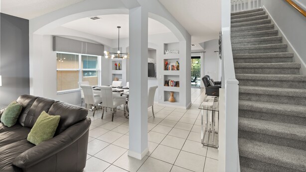 A modern interior with a staircase, a dining area, and a living room with a leather sofa. - ✦ 5min to Disney ✦ 6BR/5.5BA ✦ Private South Pool ✦ A/C Game Room ✦ Sleeps 14 (Kissimmee)