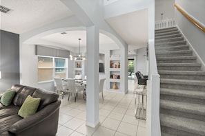 A modern interior with a staircase, a dining area, and a living room with a leather sofa.