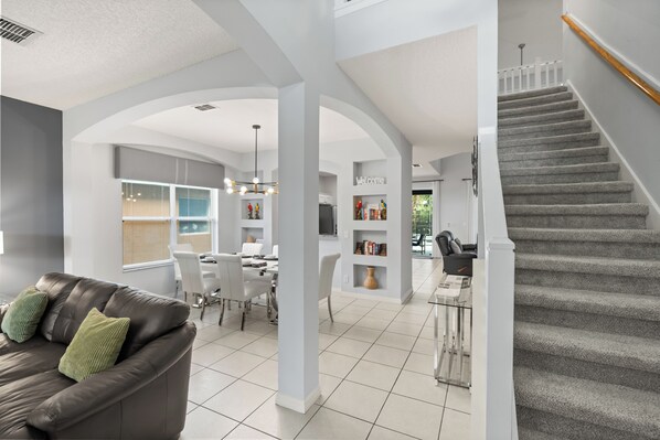 A modern interior with a staircase, a dining area, and a living room with a leather sofa.