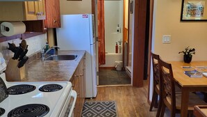 Une cuisine de taille réduite, dotée de meubles en bois, d’une cuisinière et d’un coin repas avec une table et des chaises.