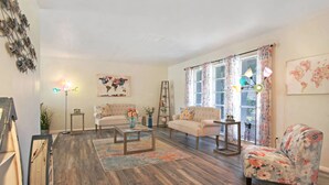 Un salon avec deux canapés, une table basse, un tableau représentant une carte du monde et une échelle appuyée contre le mur.