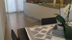 A modern kitchen with a gas stove, a coffee maker, and a sink. There is a dining table with a patterned tablecloth and a potted orchid. - At the Court of Bertoli SPA - Lena House (Canale)
