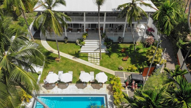 An aerial view of a resort with a pool, lounge chairs, and palm trees. - Plantation House (Hikkaduwa)