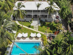 An aerial view of a resort with a pool, lounge chairs, and palm trees.