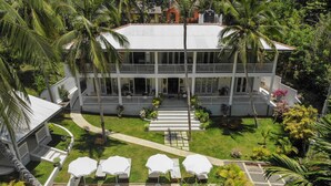 A two-story building with a swimming pool, surrounded by palm trees and a well-maintained lawn. - Plantation House (Hikkaduwa)