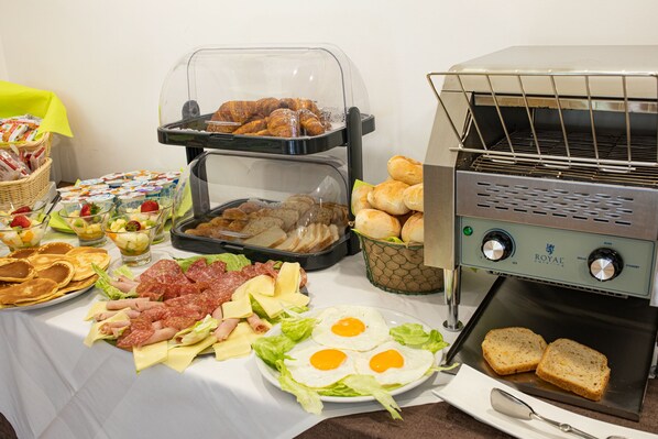 A buffet with various food items including bread, eggs, meats, and salads.