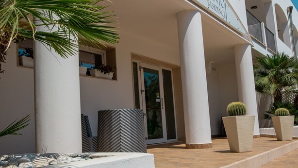 A hotel entrance with a modern design, featuring a signboard, a pathway with white and grey stones, and potted plants. - Ground Floor Double Room in "Donnosanto Residence" (Torre Santa Sabina)