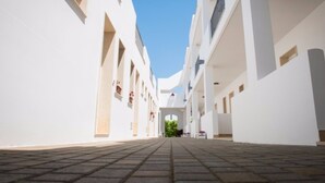A long, straight corridor with white walls and a tiled floor, leading to a central open space with greenery. - Ground Floor Double Room in "Donnosanto Residence" (Torre Santa Sabina)